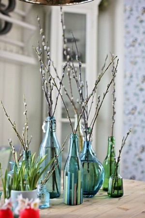 Branches de saules en bourgeon dans des bouteilles en verre bleu et vert