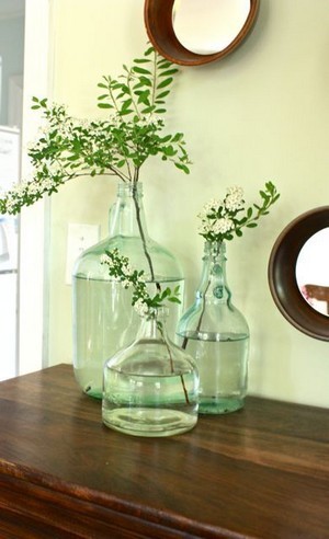 Branches et fleurs dans des carafes et bouteilles en verre