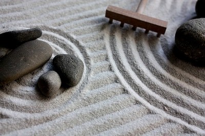 jardin zen sec avec du sable, des galets et un rateau