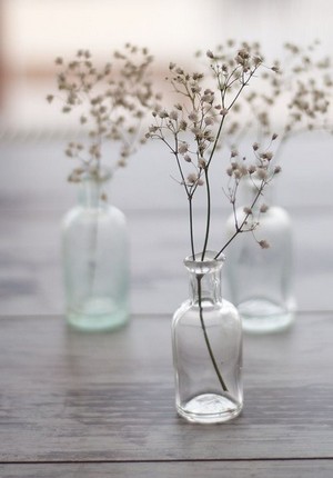 Petites fleurs blanches fines dans une bouteille en verre transparent pour un bouquet aérien