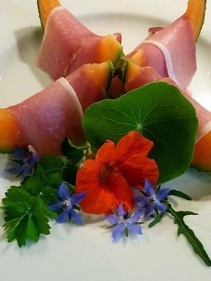 Recette de fleurs comestibles: bourrache bleue, capucine orange avec du jambon de parme et du melon. En savoir plus: lisez l'article sur le blog.